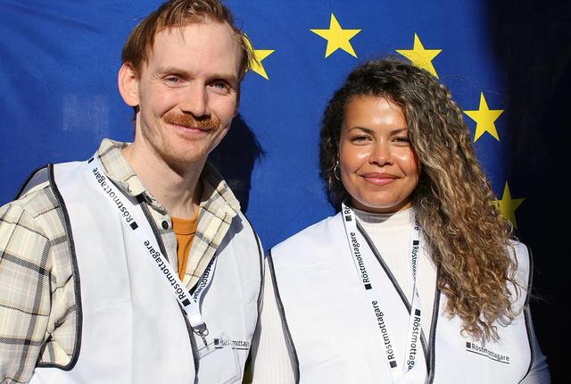 En man och en kvinna ler framför en EU-flagga.