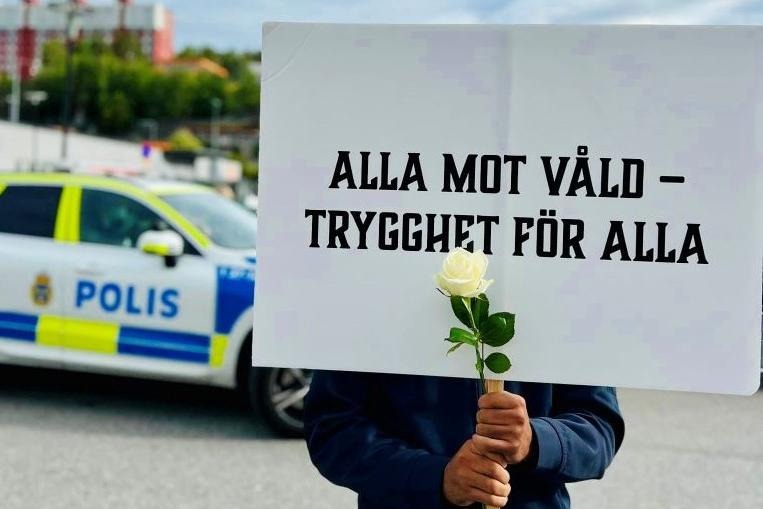 En person som håller upp en skylt med texten "Alla mot våld - trygghet för alla".