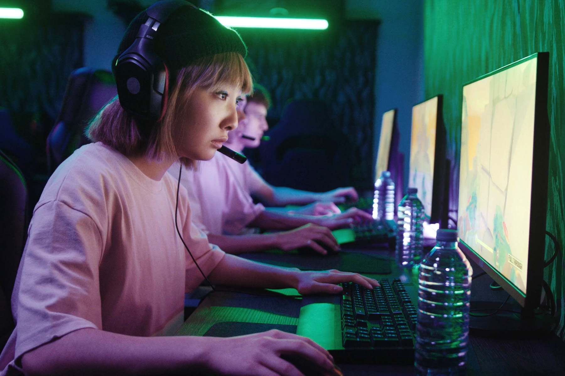 Tre personer med hörlurar som spelar på sina datorer.