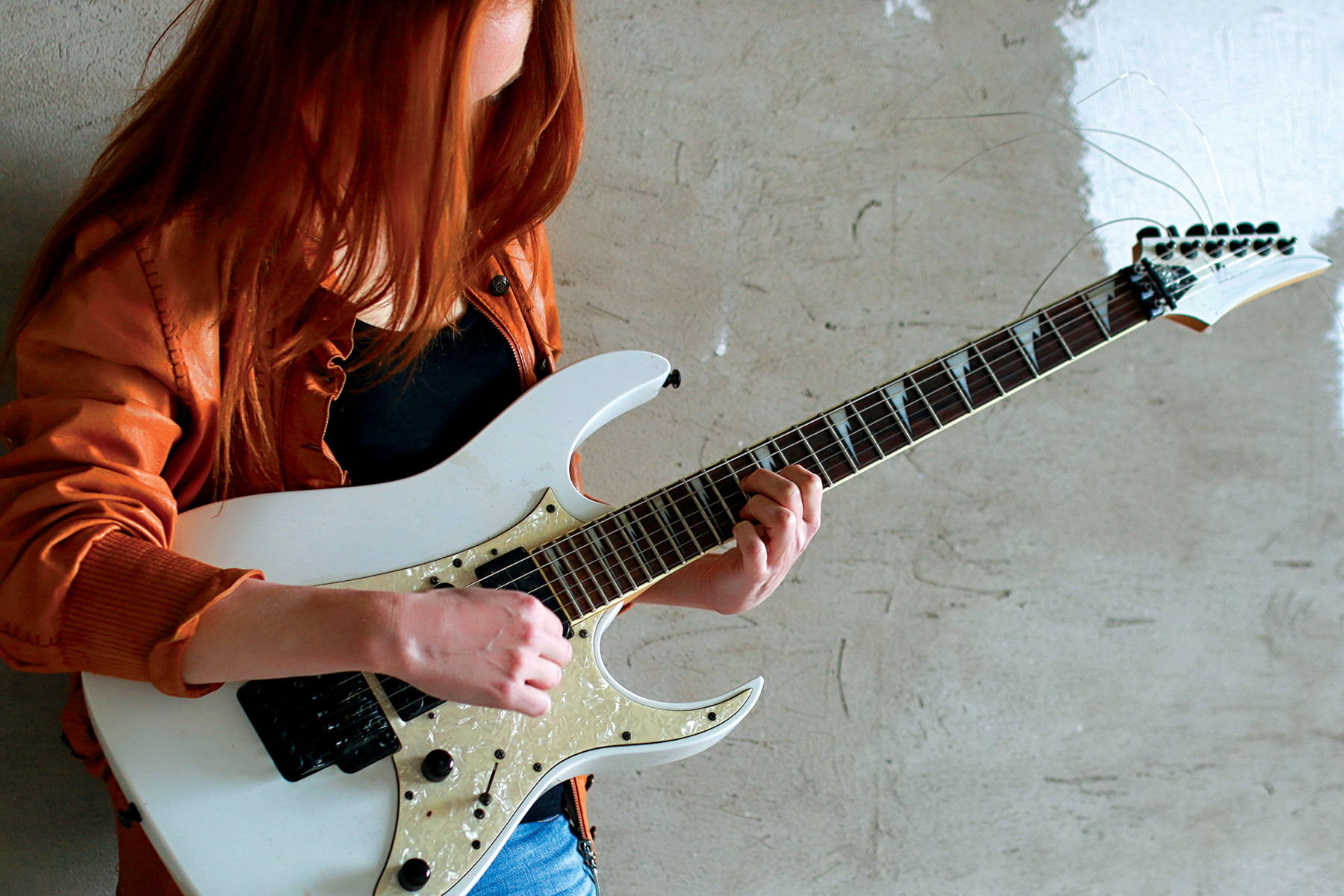 En kvinna spelar på en elgitarr.