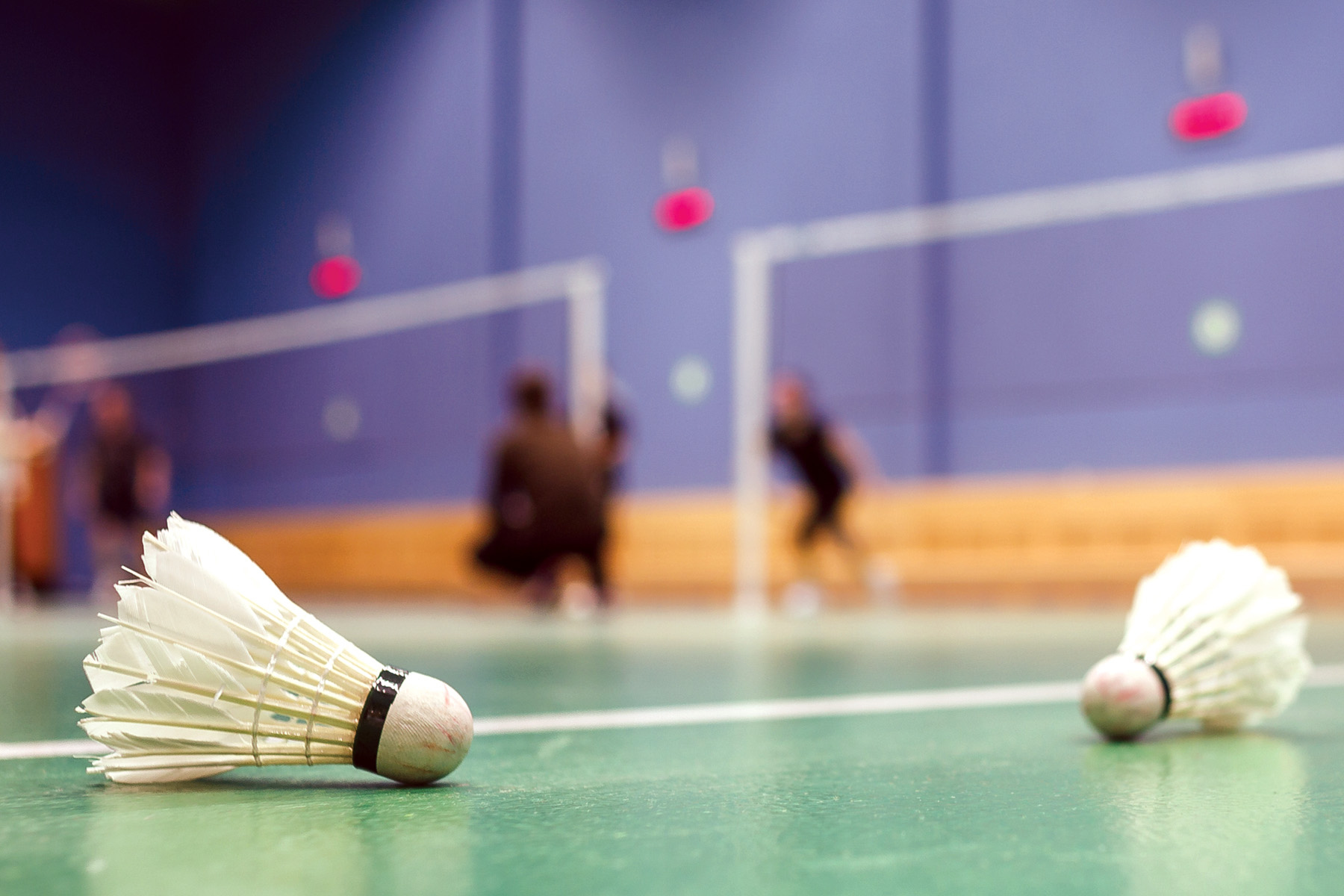 Två badmintonbollar som ligger på golvet i en träningssal.