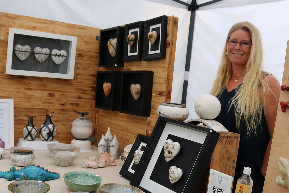 En kvinna poserar tillsammans keramikskålar och hjärtan.